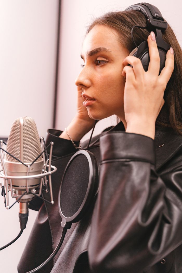 Crafting Captivating Headlines: Your awesome post title goes here A woman wearing headphones and leather jacket recording vocals in a studio.